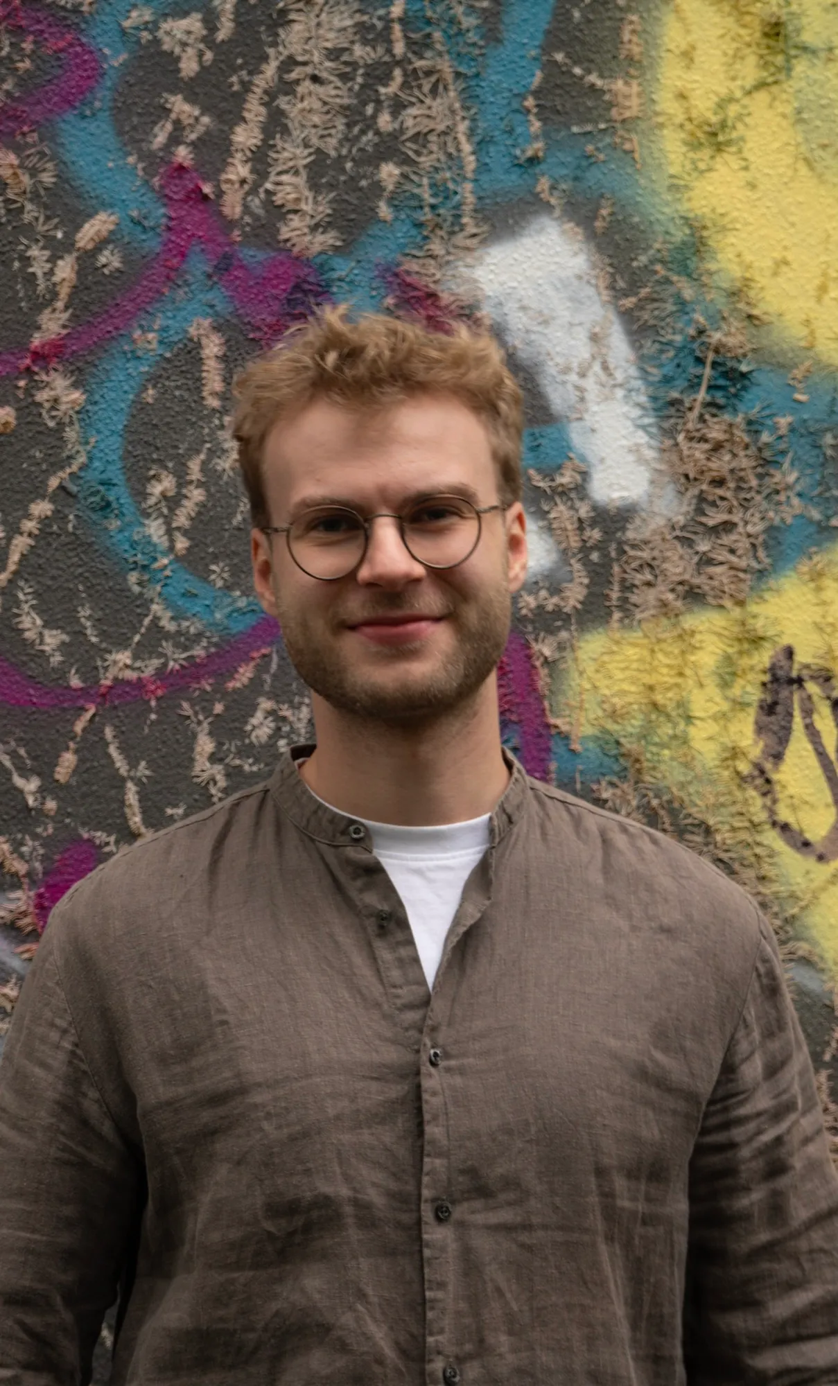 Portræt af Thomas Enemark Staugaard foran en væg med graffiti